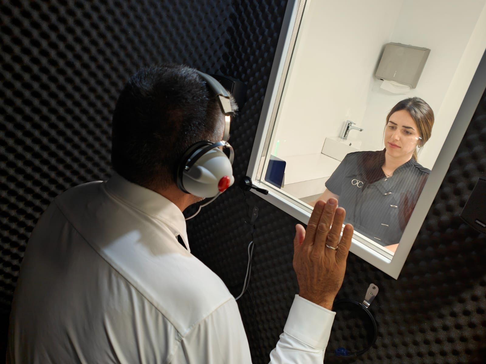 Prova d’audiometria a la cabina insonoritzada, amb una professional observant des de fora